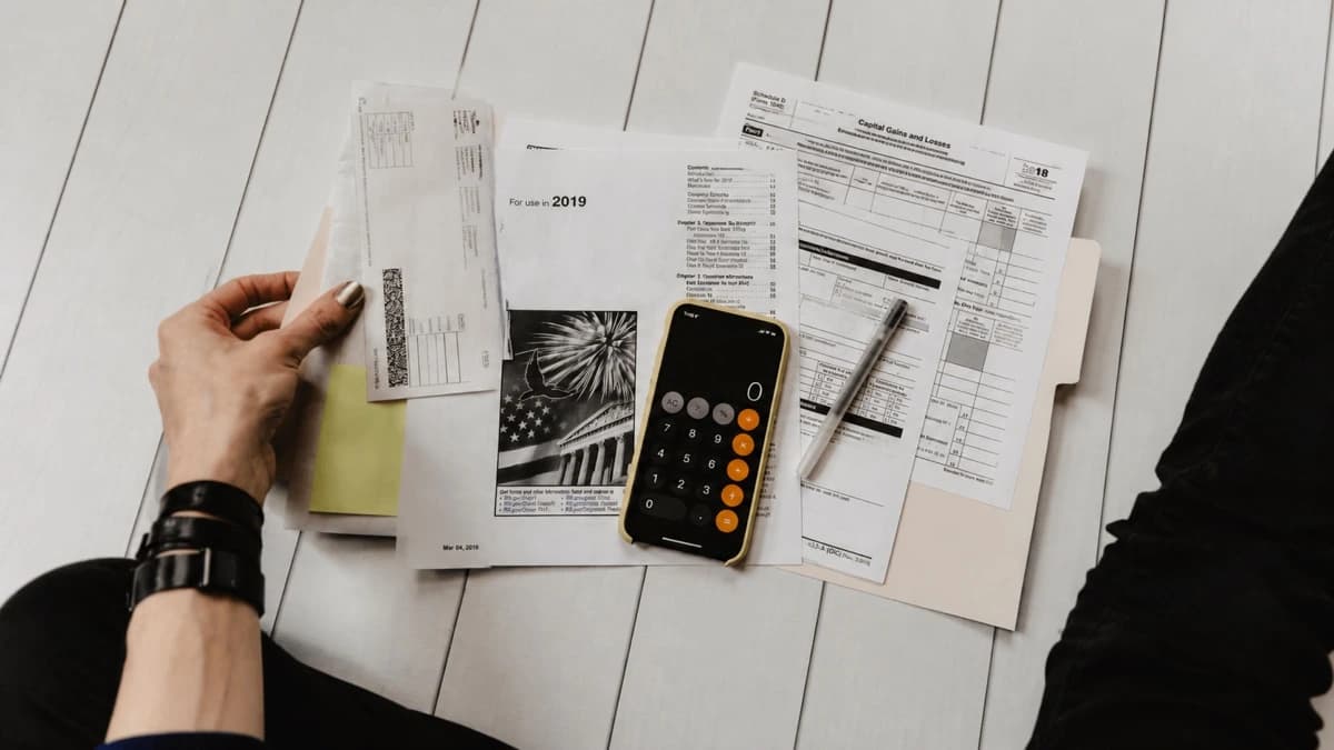Hand reviewing receipts and financial documents beside a calculator